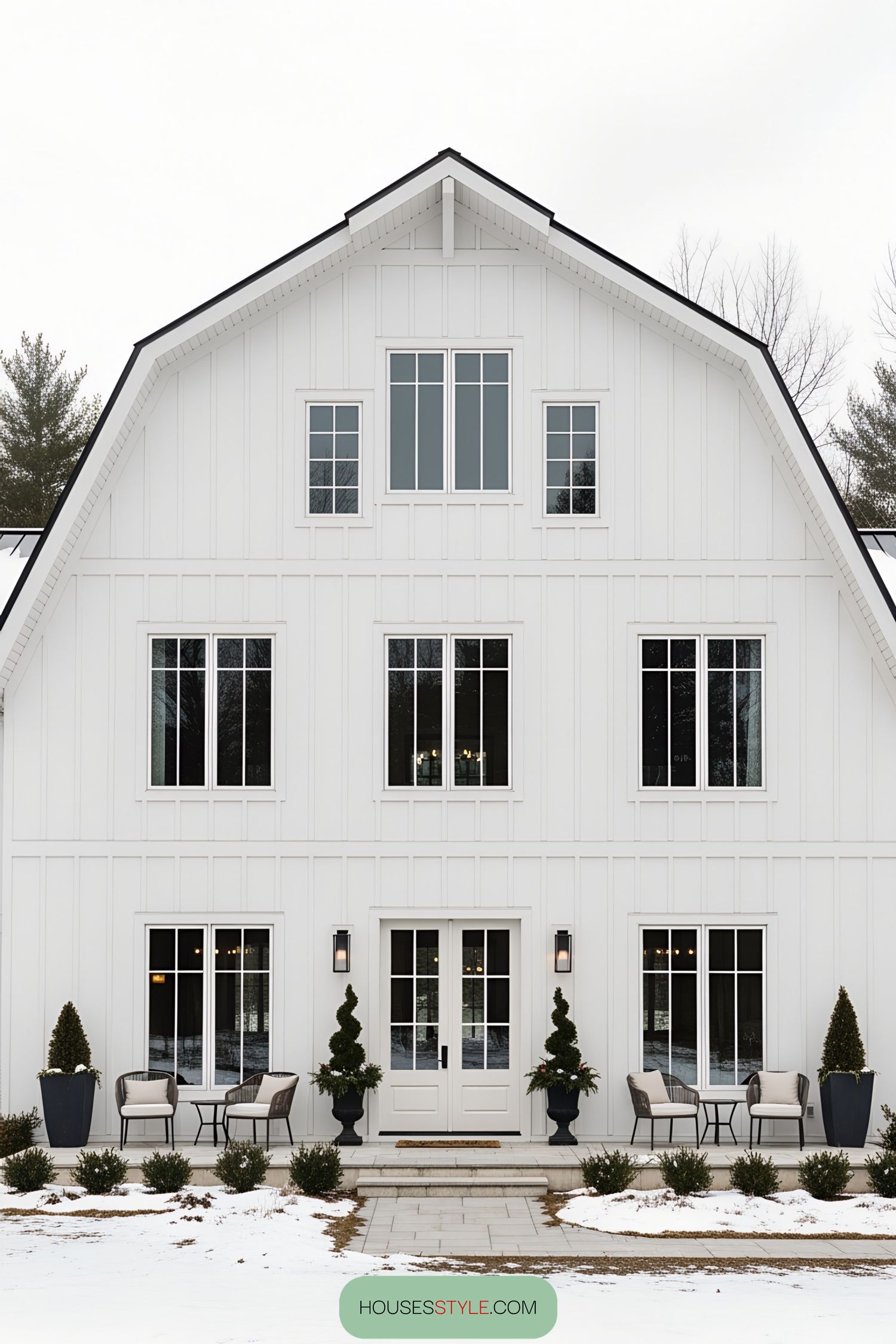 White barn house with large windows and snow-covered ground