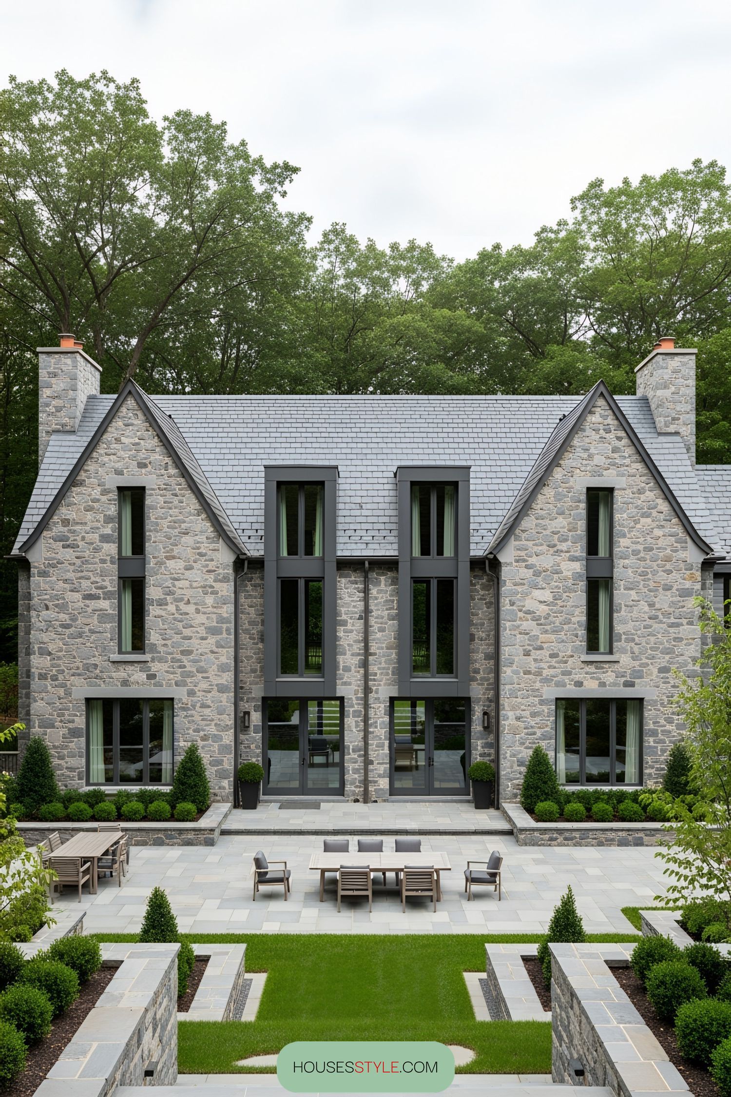 Front of a stone house with large windows and a symmetrical design