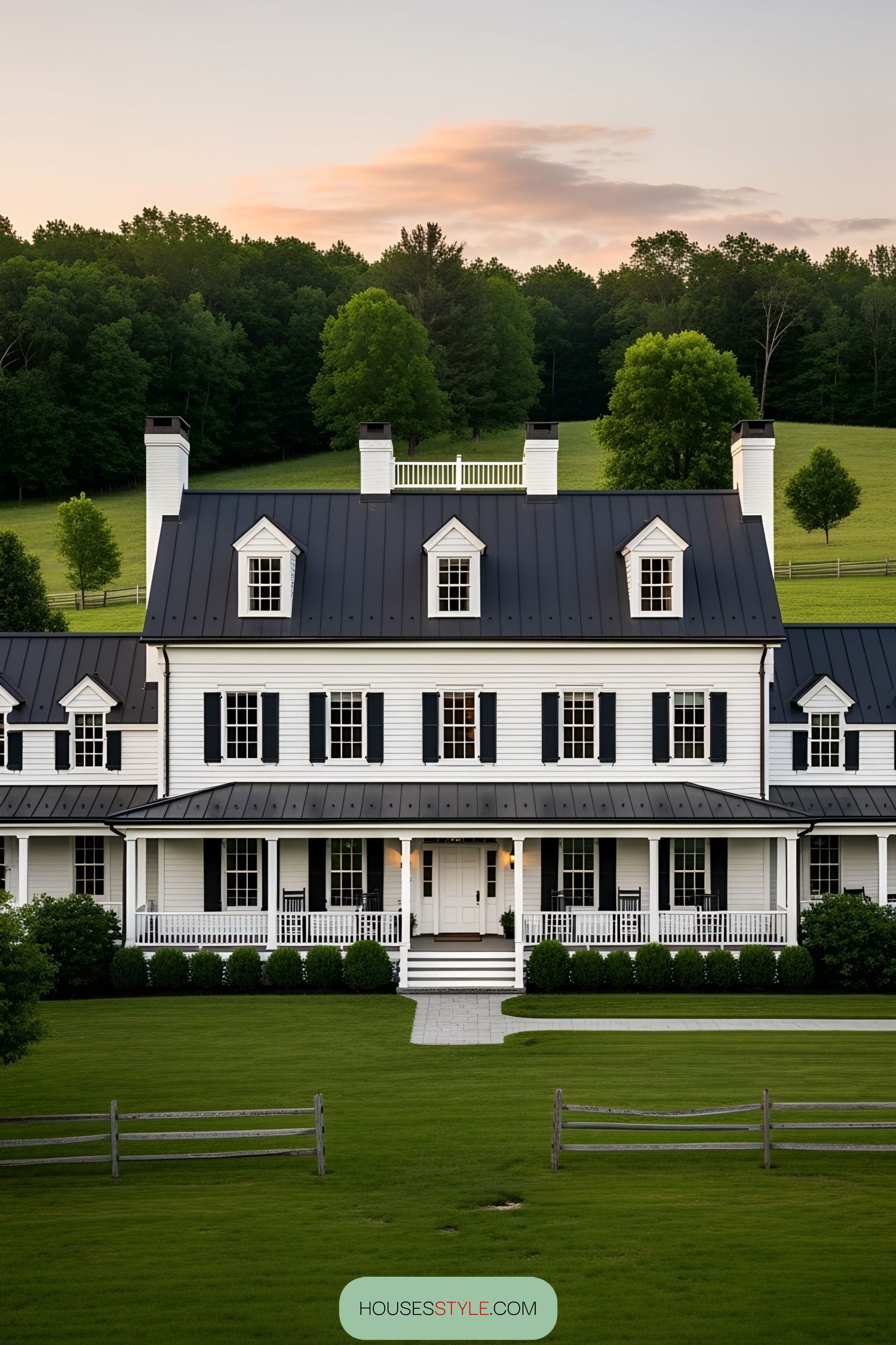 White barn house with dark roof amidst lush greenery