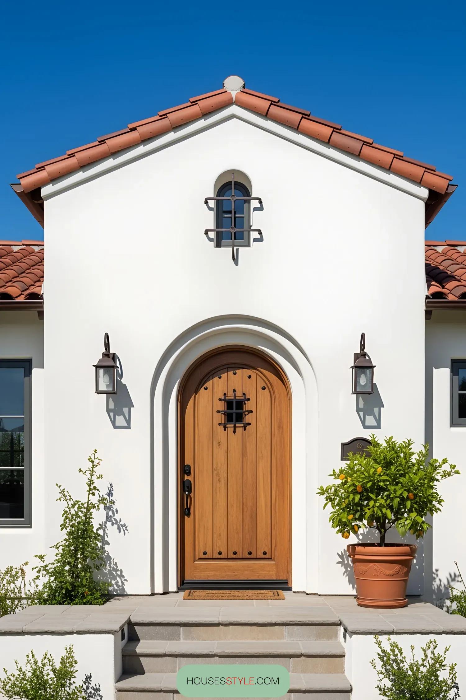 Bright white house with a wooden arched door and terracotta roof tiles