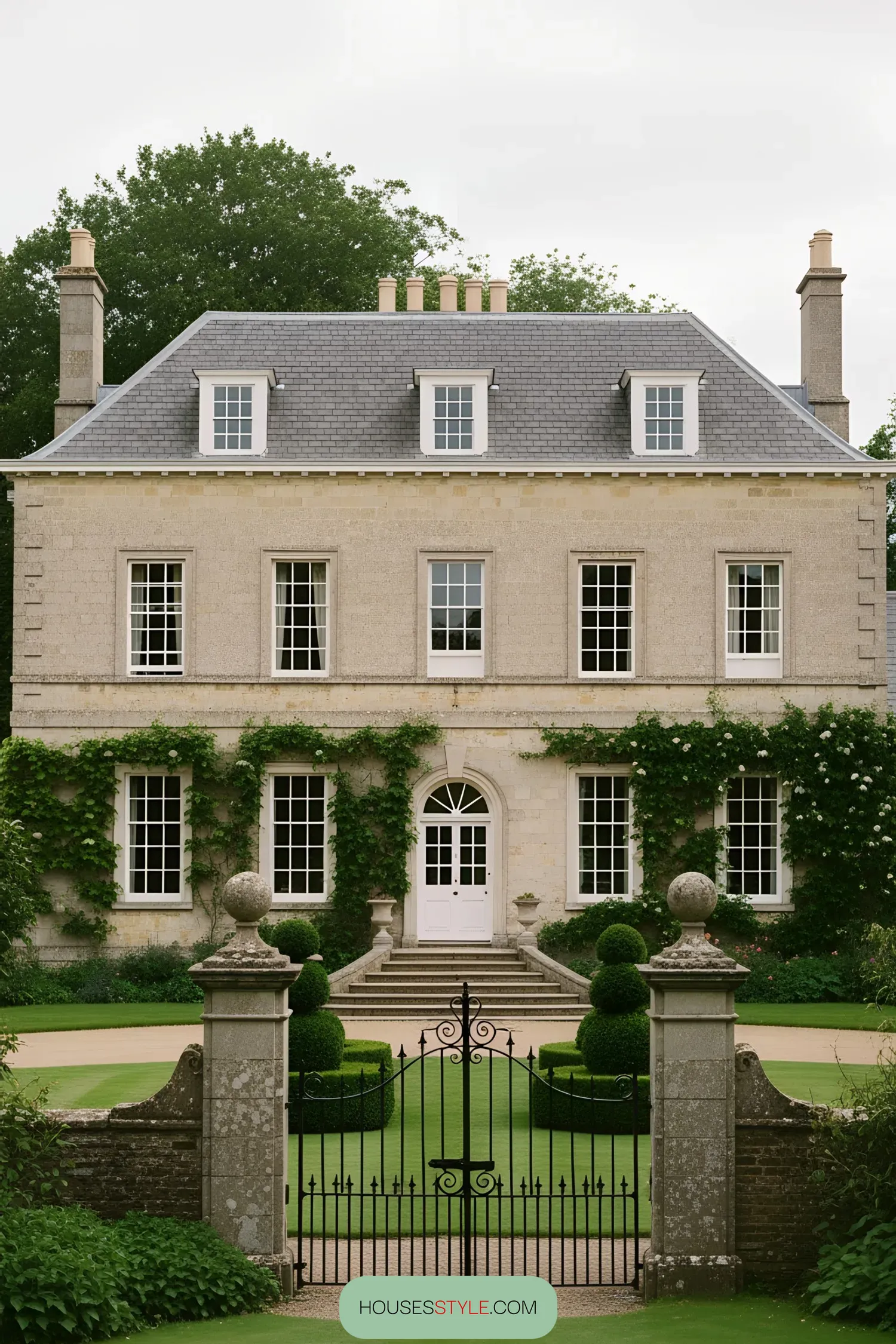 Country manor flanked by lush greenery and wrought iron gate