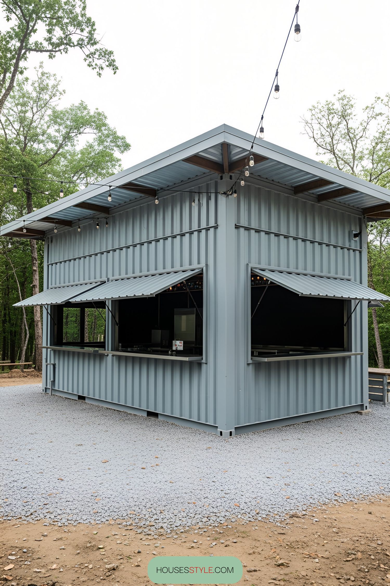 A gray container bar surrounded by trees and string lights