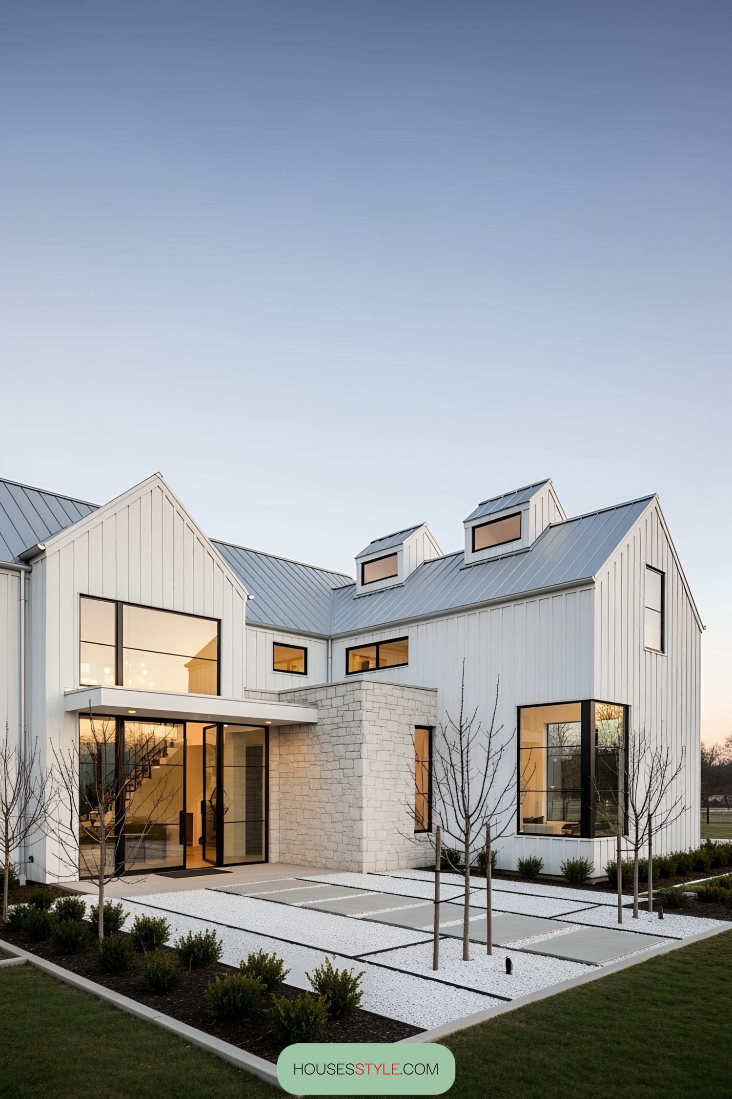 White barn house with large windows and a stone accent wall