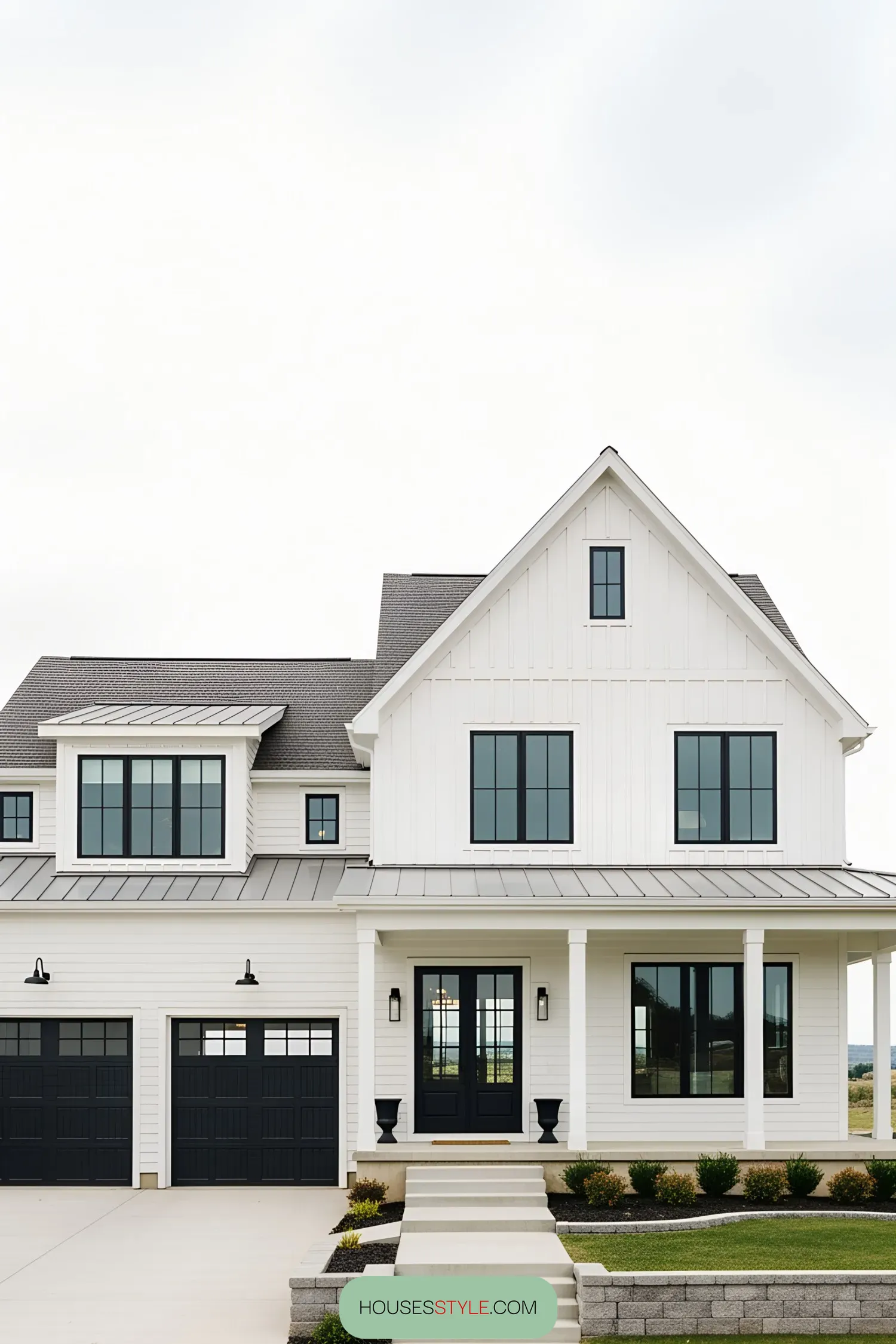 White farmhouse with black garage doors and clean landscaping
