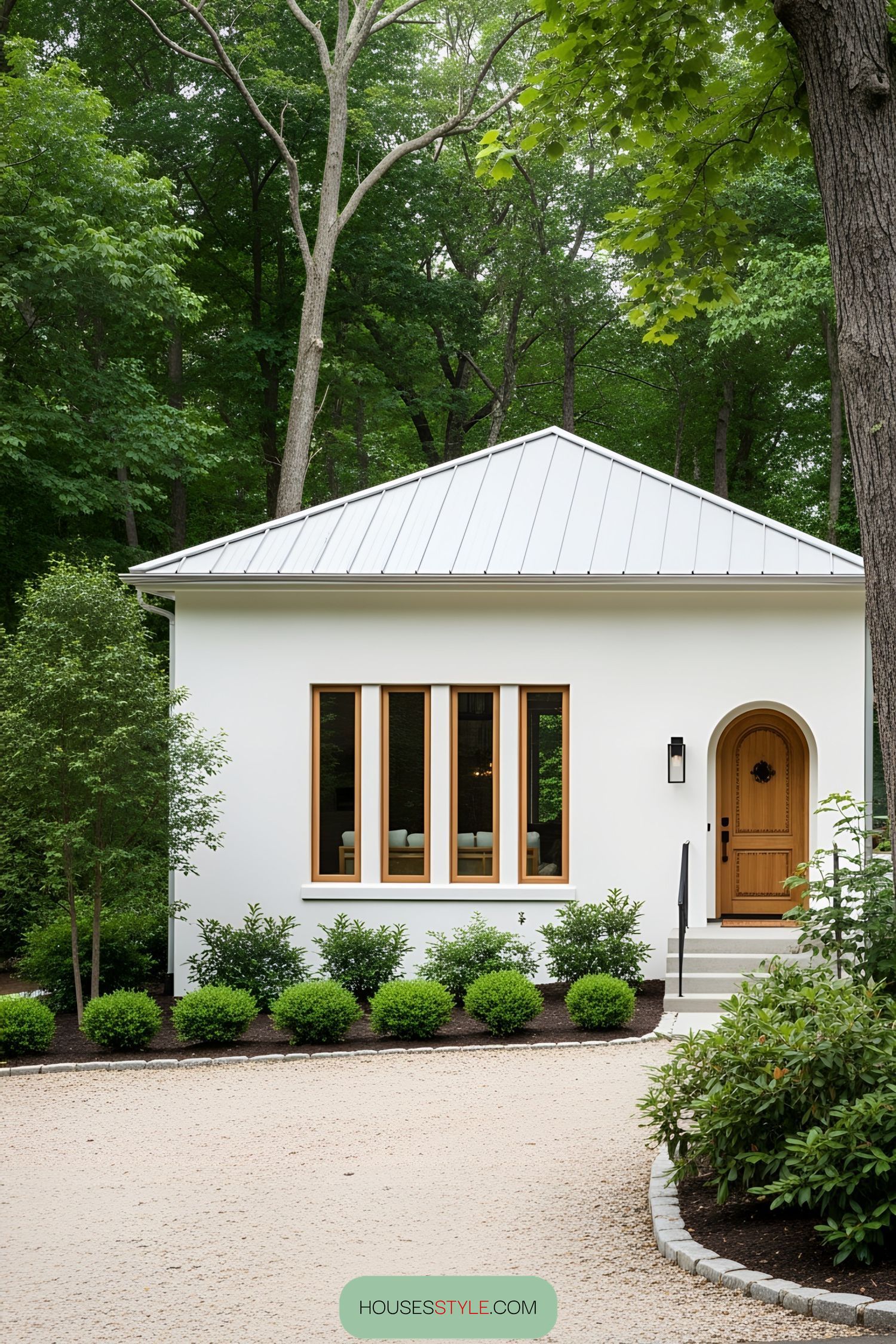White bungalow with arched doorway and large windows surrounded by greenery
