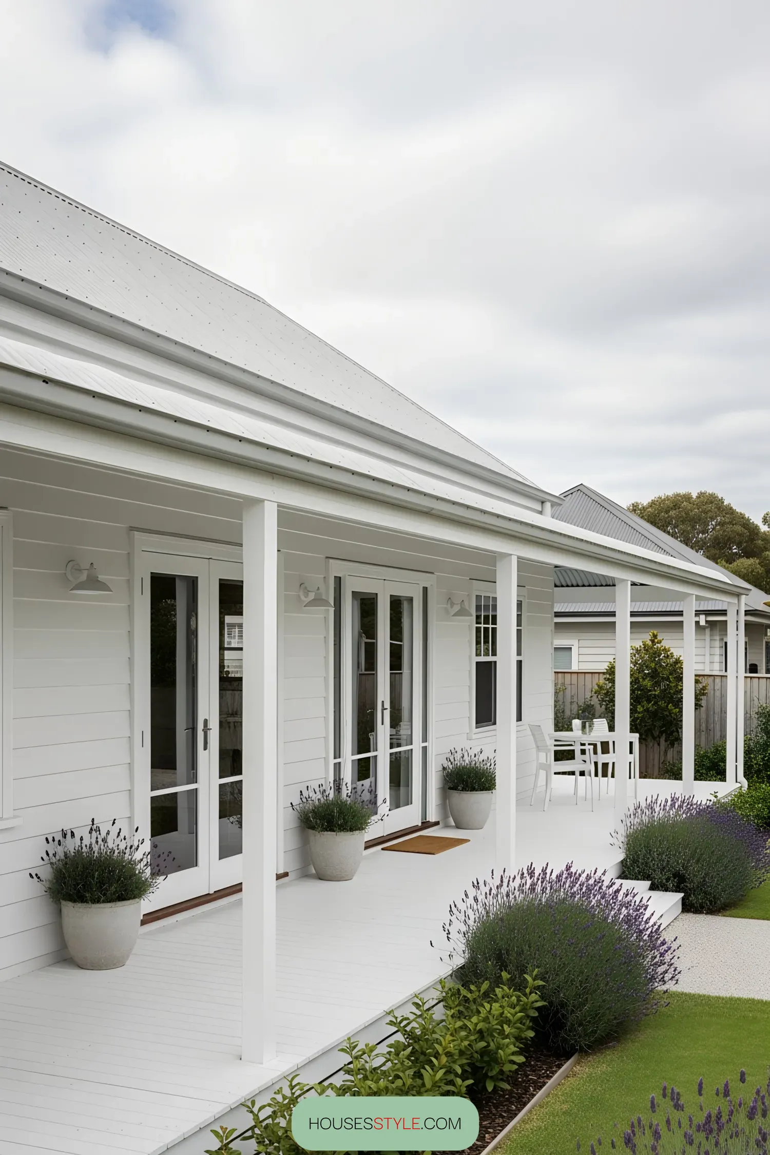 White coastal house with a charming porch and lush garden