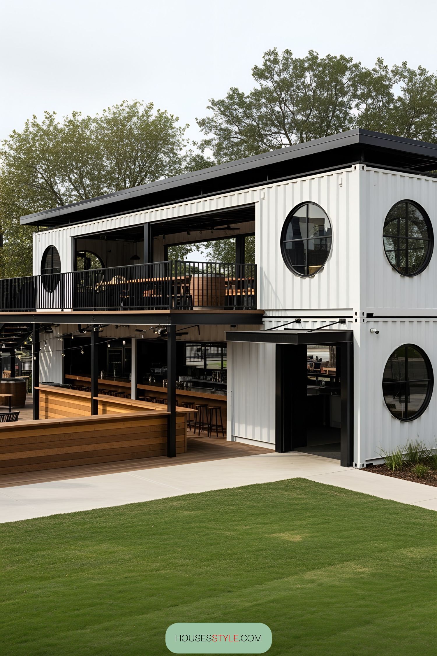 Two-story white container bar with circular windows and outdoor seating