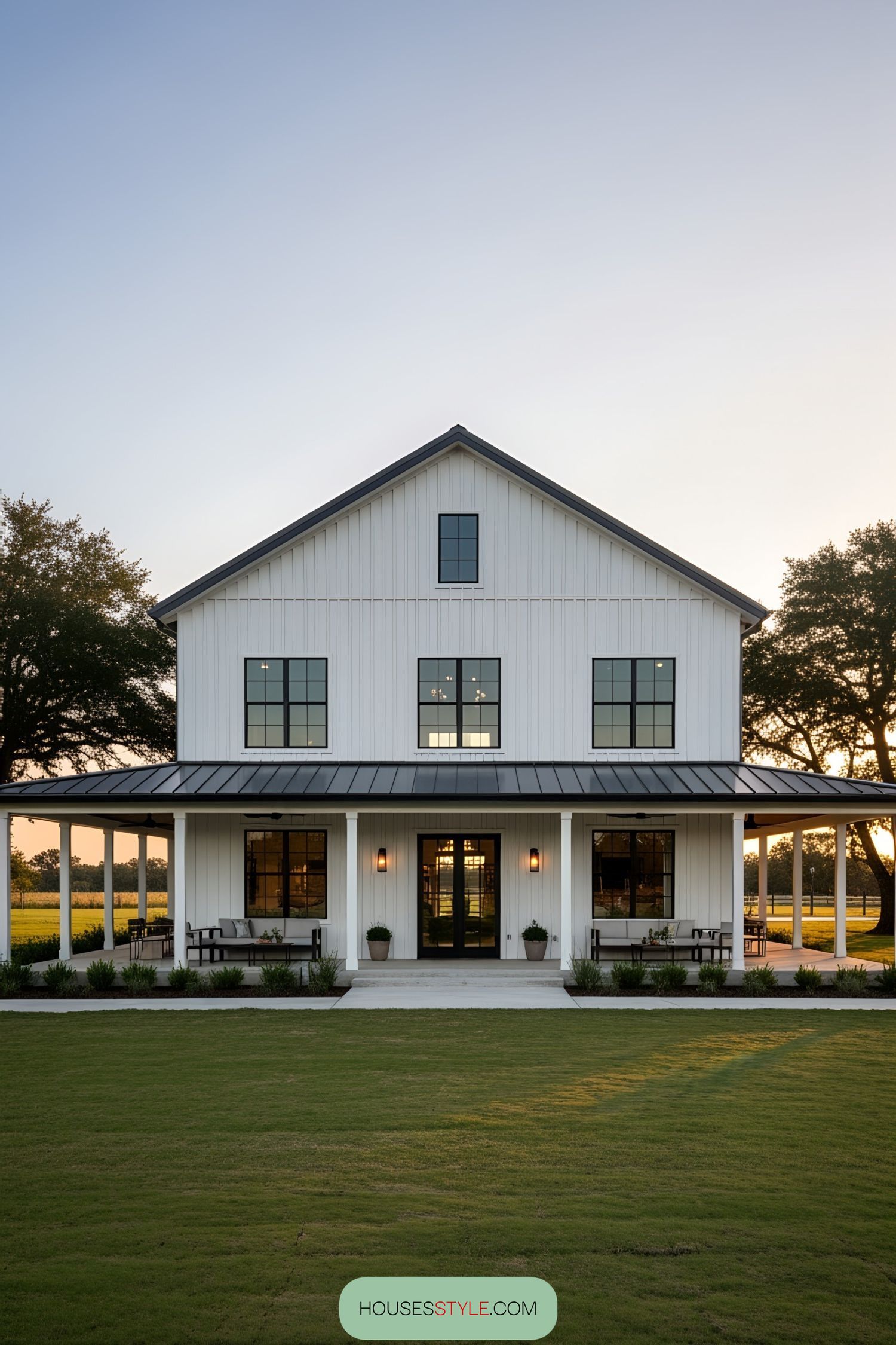 White barnhouse with a wraparound porch and sunset view