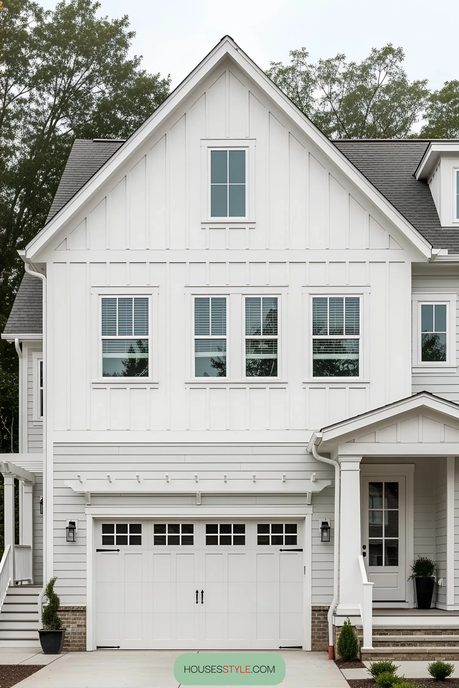 White farmhouse with attached garage and trees in the background