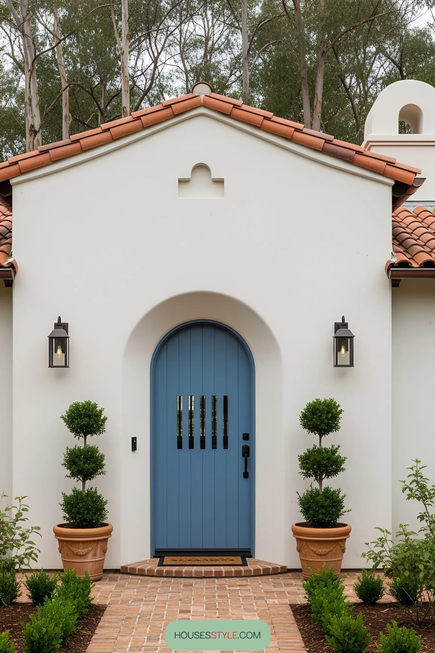 White coastal house with a blue door and terracotta roof