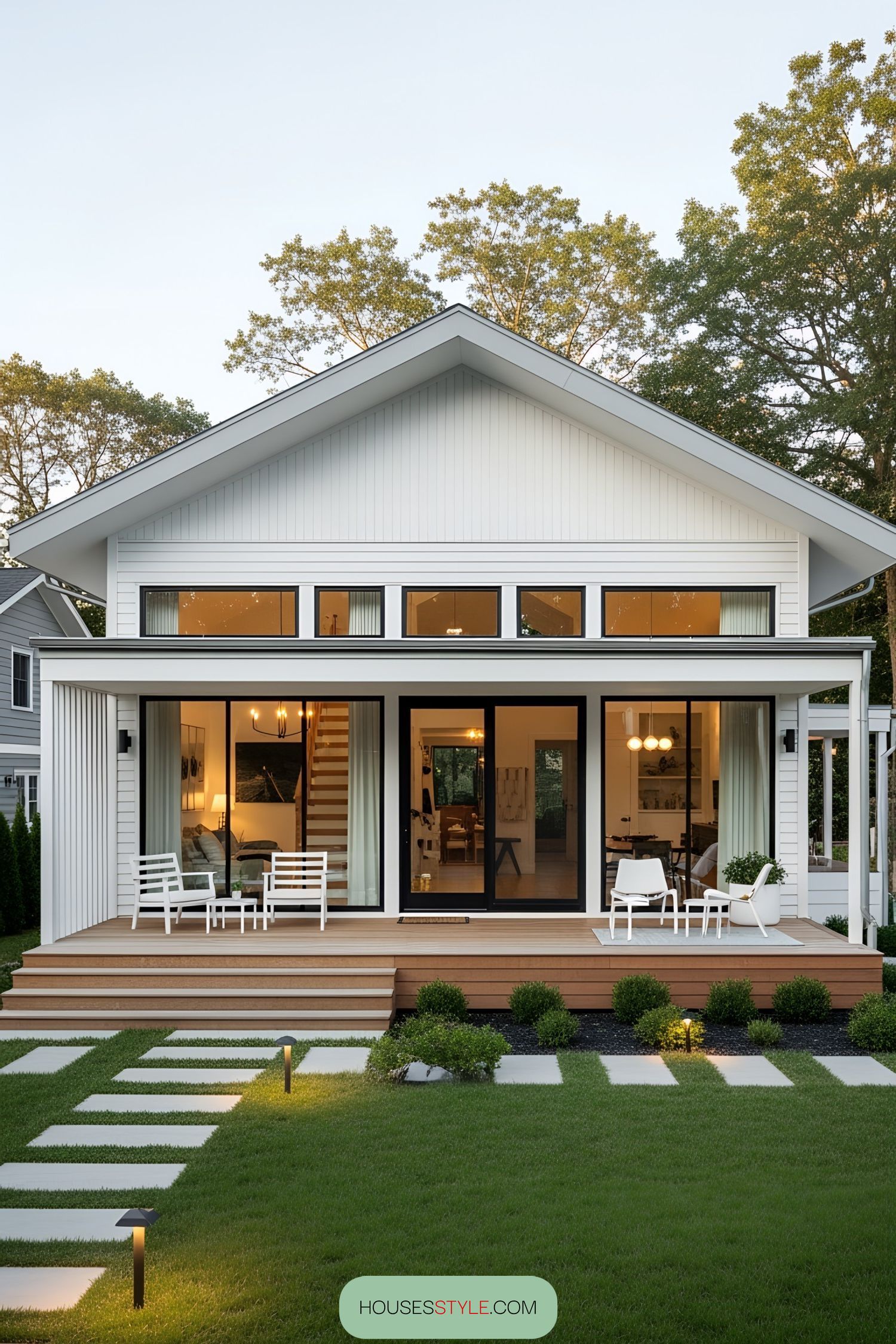 Stylish white bungalow with large windows and a wooden deck
