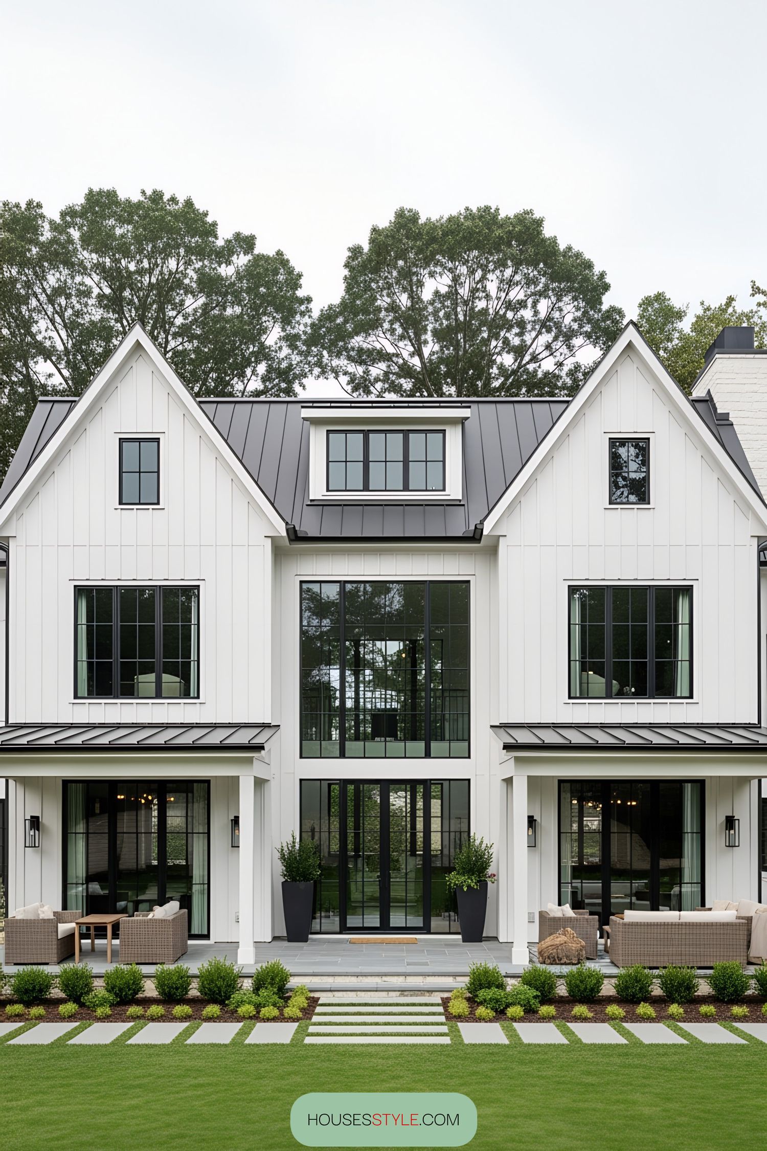 Modern white barn house with black windows and lush green lawn