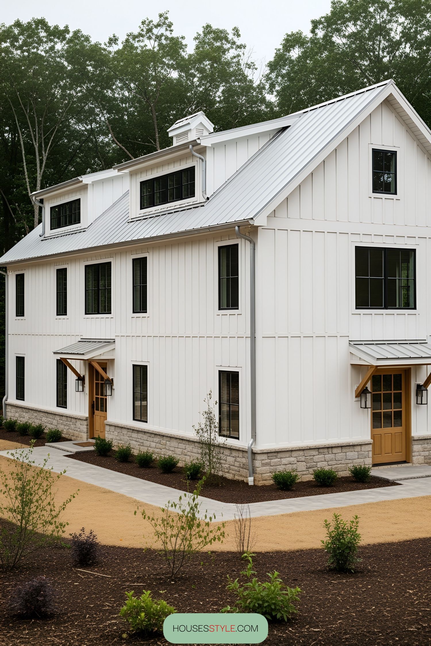 Modern white barn with black-framed windows and stone base