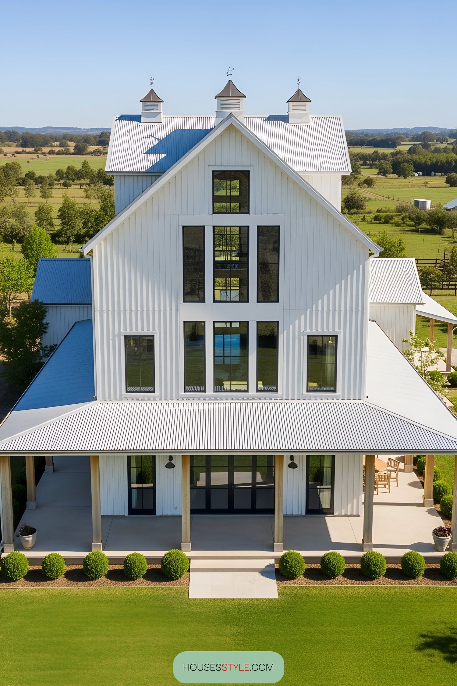 White barn house with cupolas and large windows