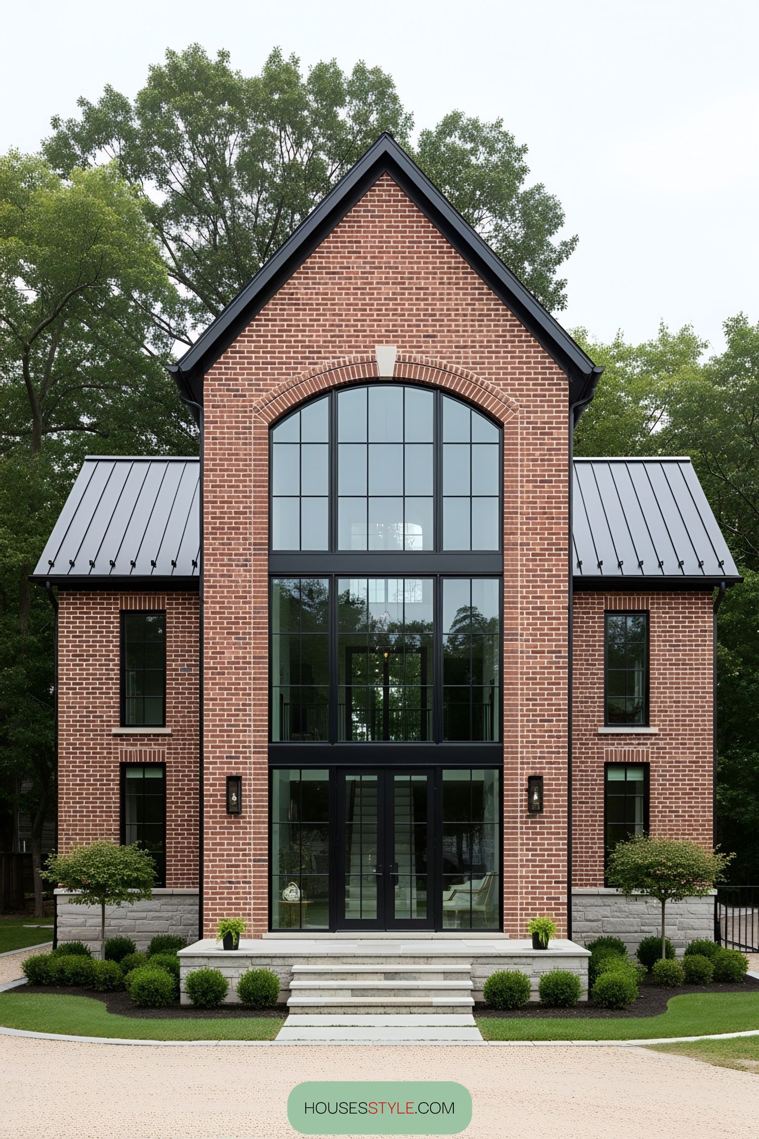 Red brick house with large arched windows and metal roofing