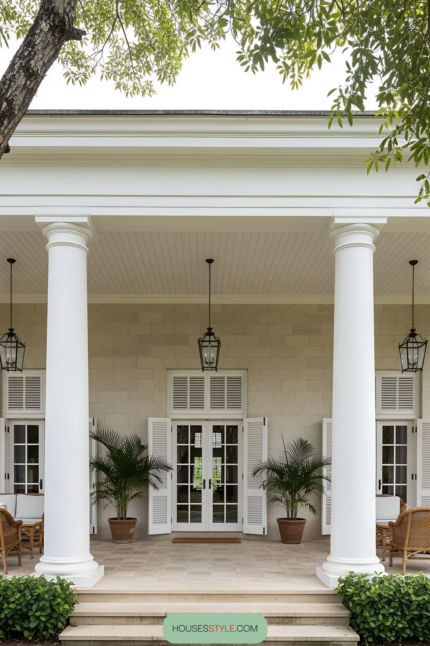 Front porch of a colonial house with large columns and potted plants