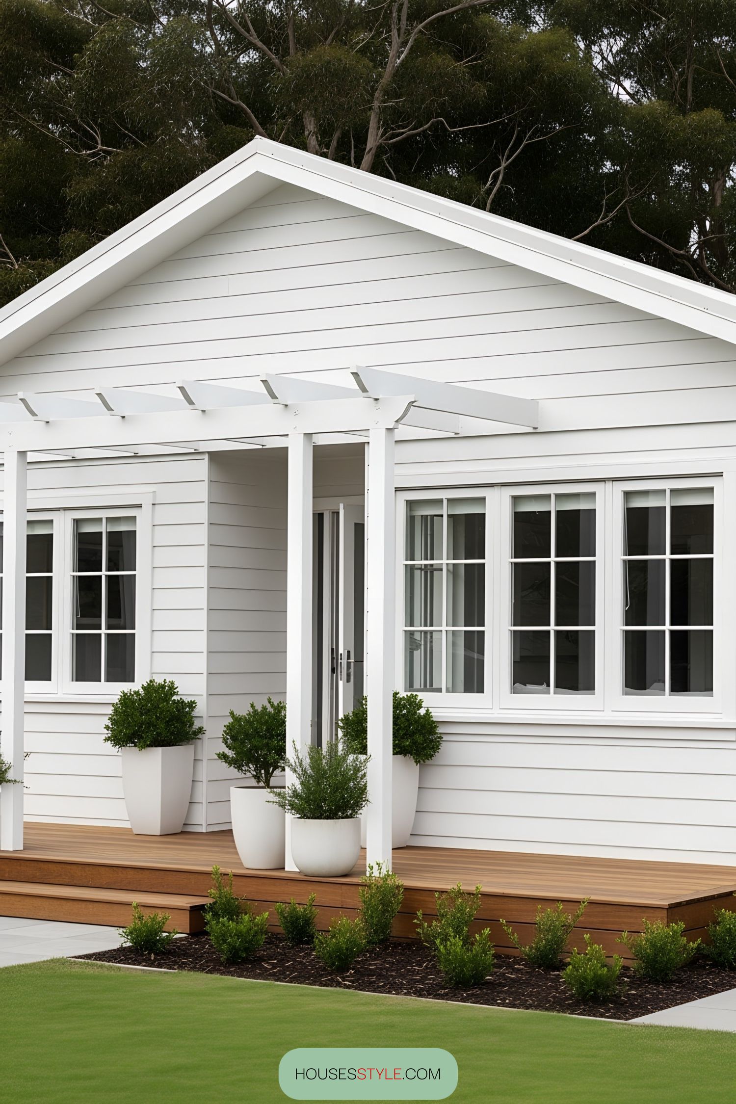 White bungalow with a wooden porch and potted plants