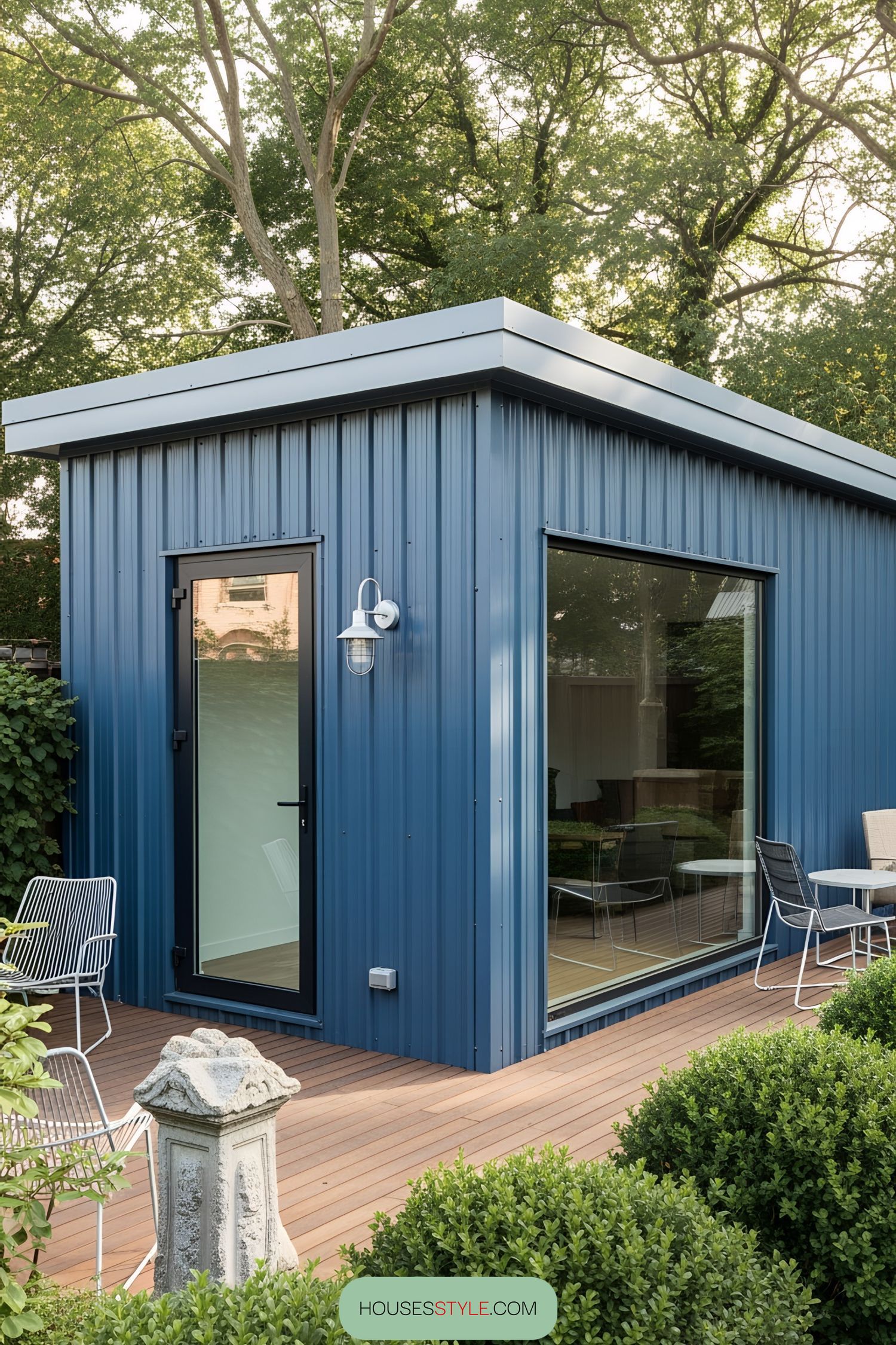 Sleek blue workshop with large windows and a cozy deck