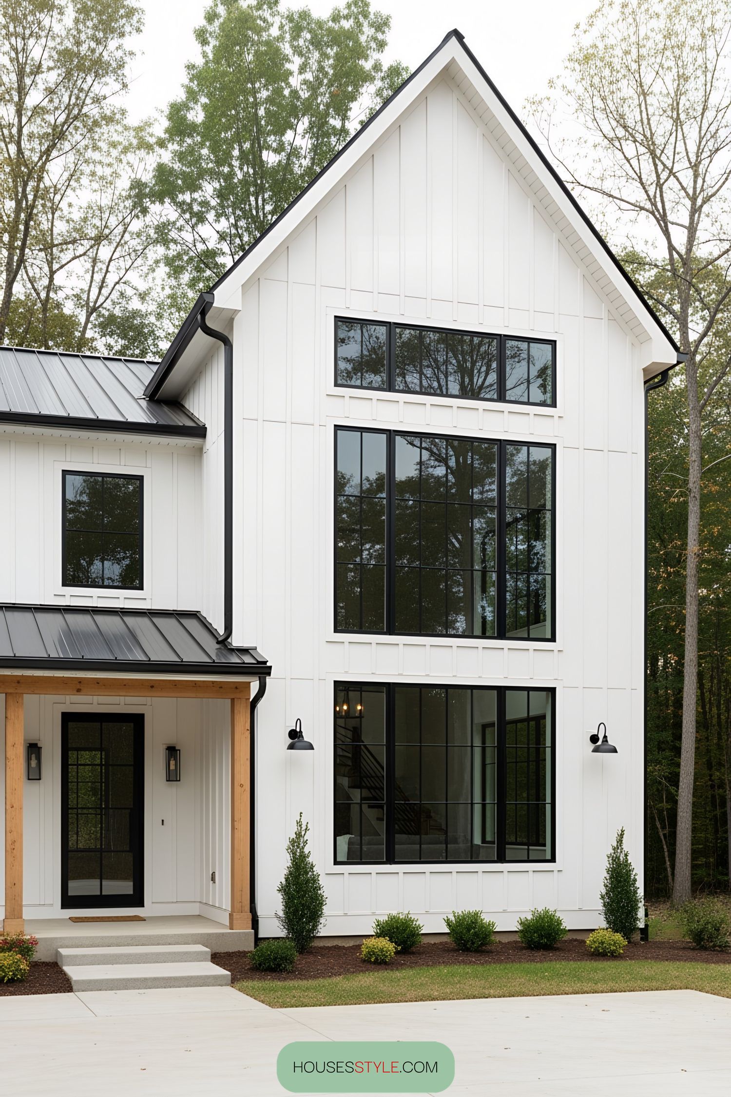 White barn house with black-framed windows and lush greenery