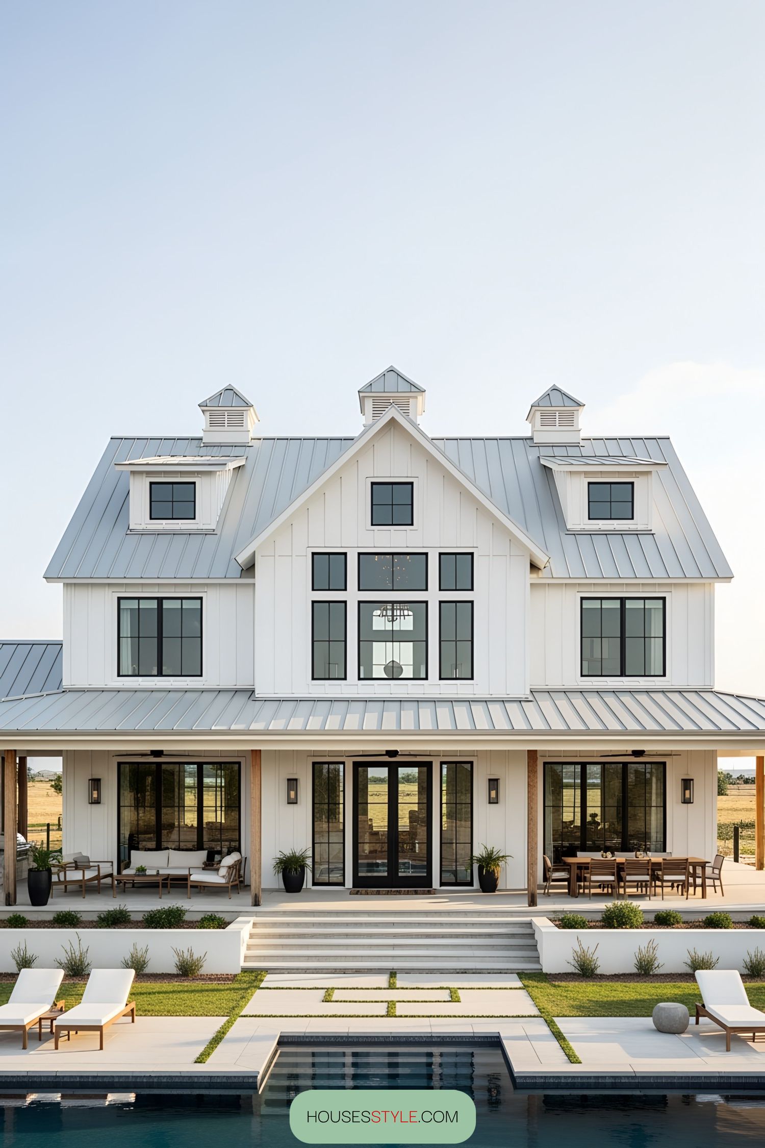 A stunning white barn-style house with a pool and patio