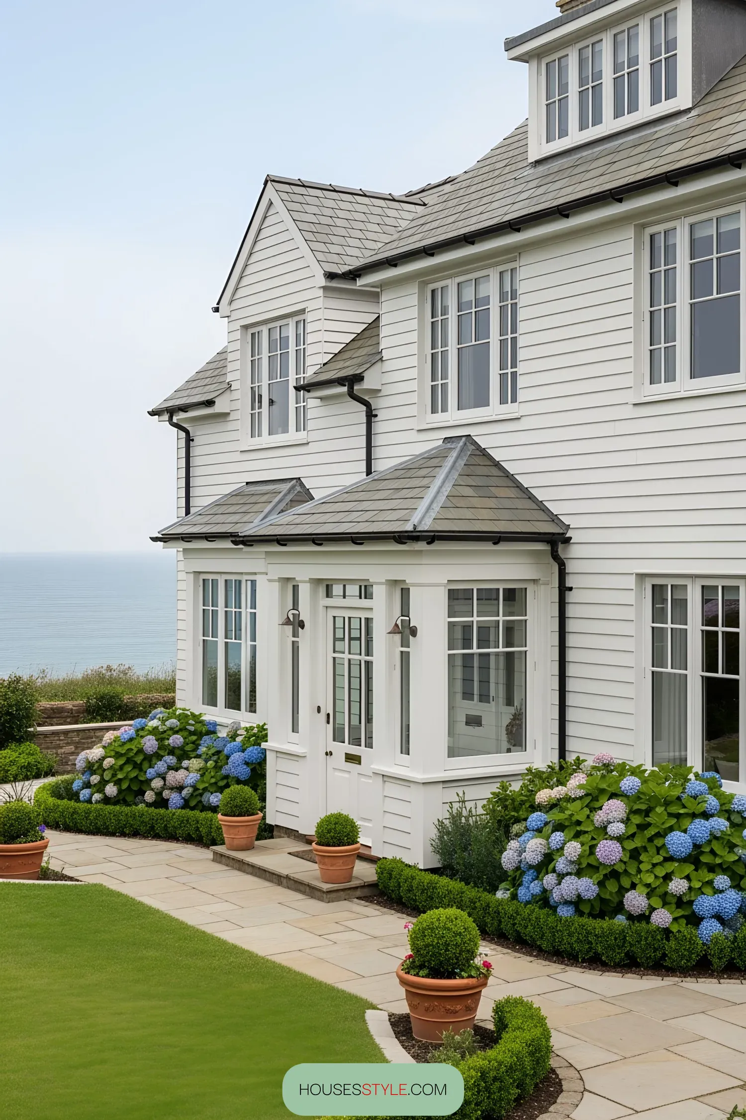White coastal house with hydrangeas, overlooking the sea