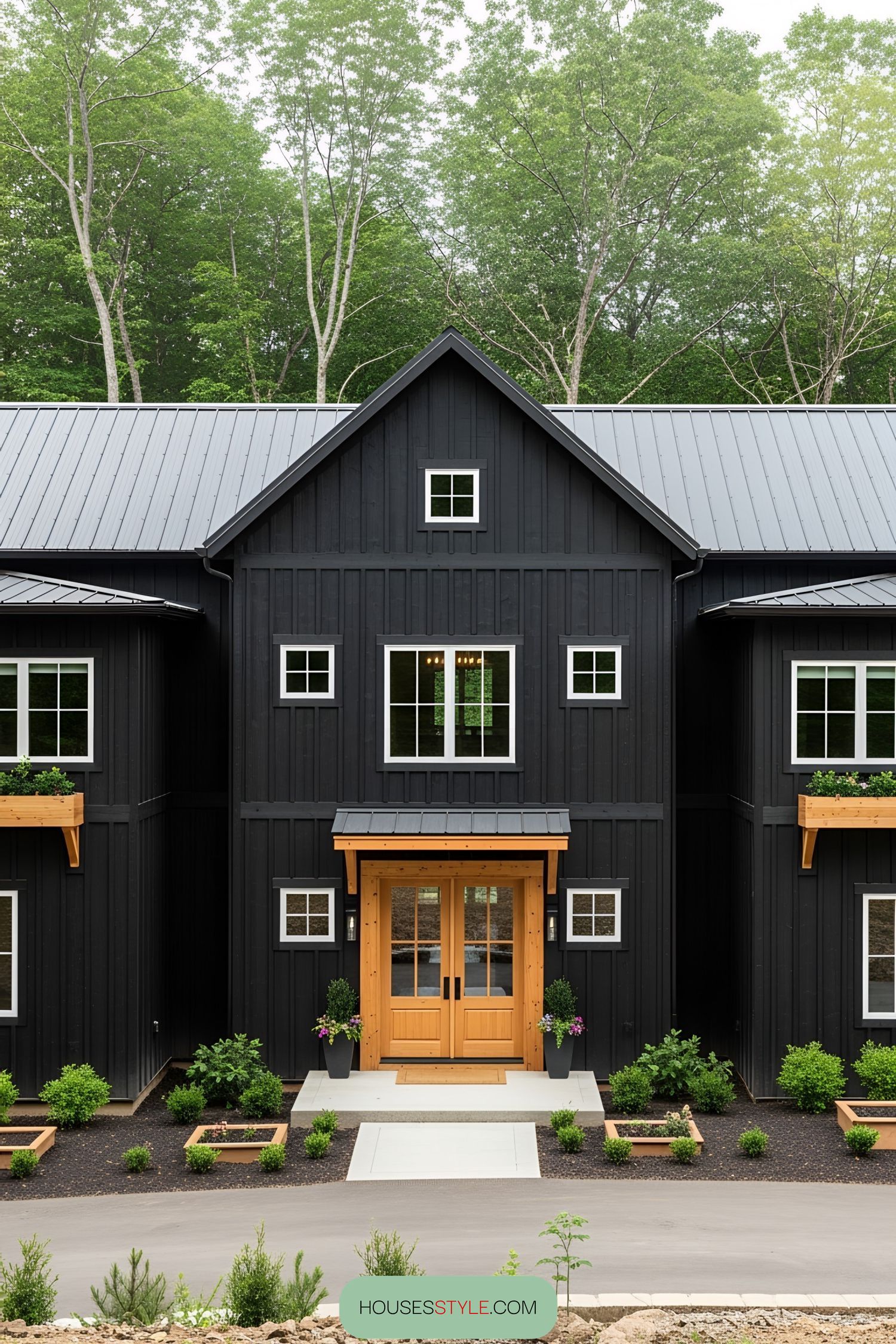 Black pole barn house with a wooden door and charming windows
